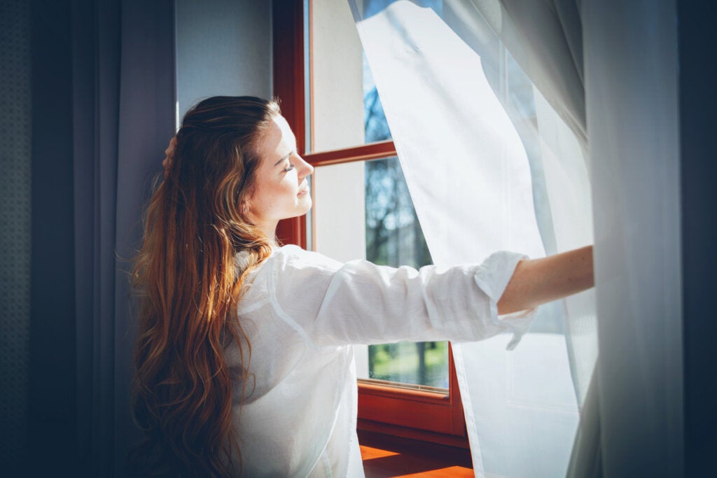 Woman opening a window to enjoy the blue light